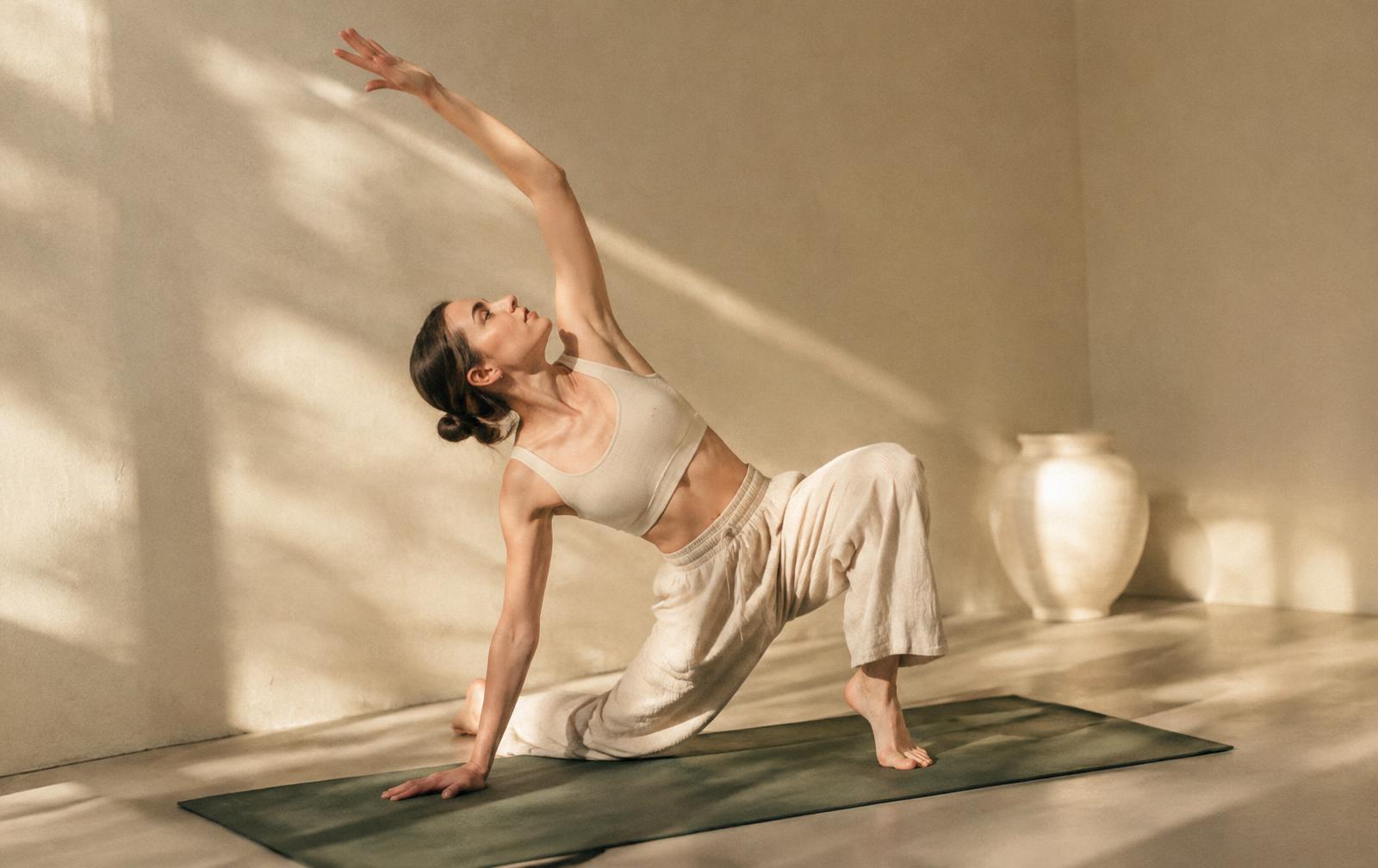 Hannah stretching on a green mat in a sunlit studio